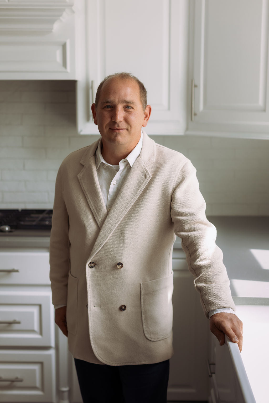 Man wearing a beige blazer in a kitchen setting